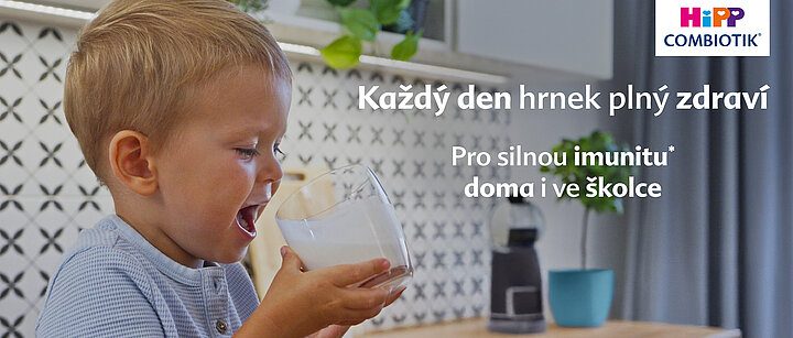 Malé dítě pije ze sklenice v moderní kuchyni.