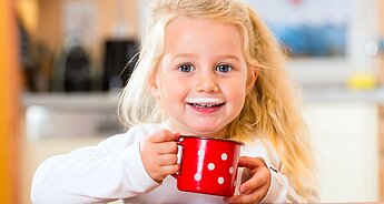 Usmívající se dívka pije batolecí mléko
