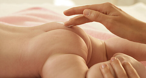 Ruka aplikuje látku na kůži dítěte.