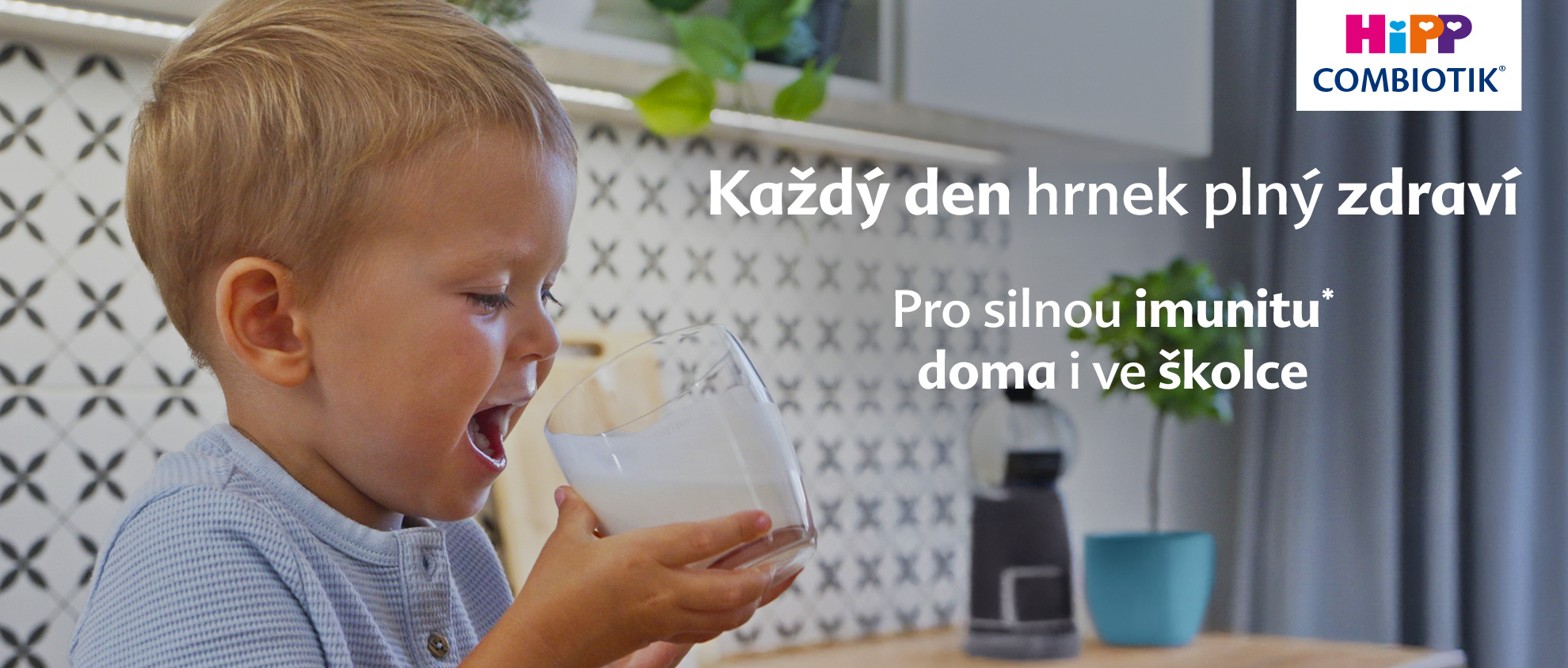 Malé dítě pije ze sklenice v moderní kuchyni.