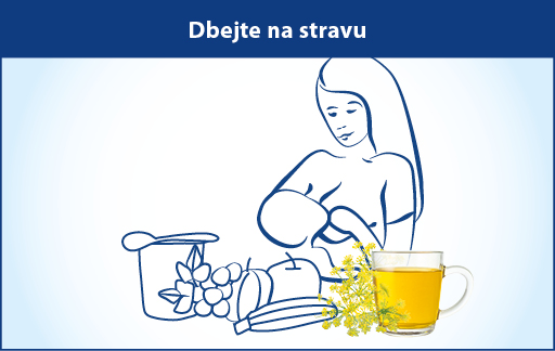 Žena krmí dítě, vedle sebe má sklenici se žlutou tekutinou a nádobu s ovocem a zeleninou.