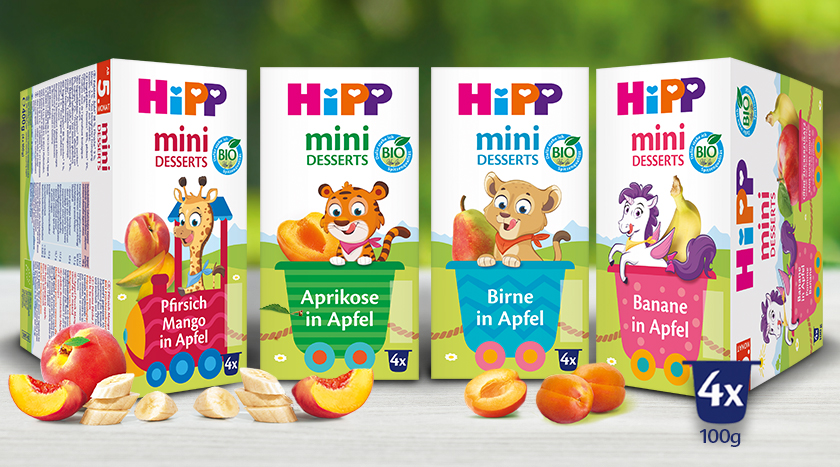 Před nimi jsou vystavena čtyři balení výrobků "Hipp mini dezerty", každé s jinou kombinací ovoce.