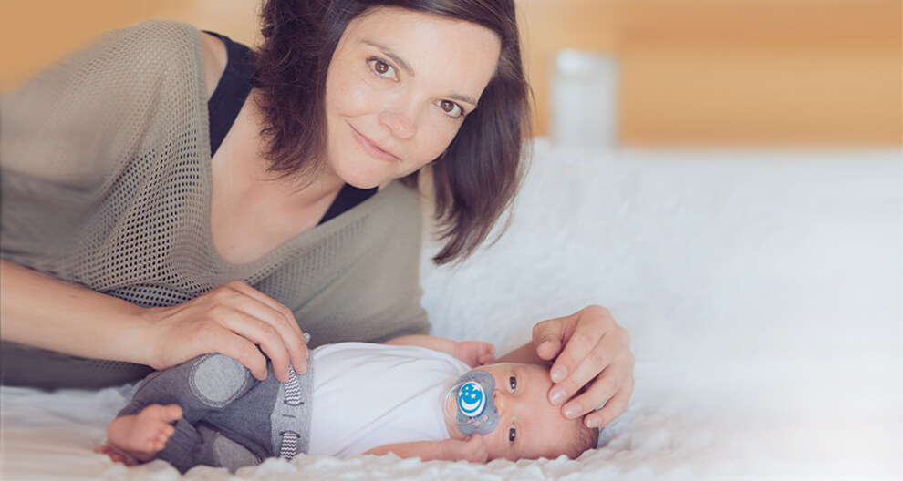 MUDr. Kateřina Karolová Žena leží na posteli a dívá se na dítě, které leží vedle ní.