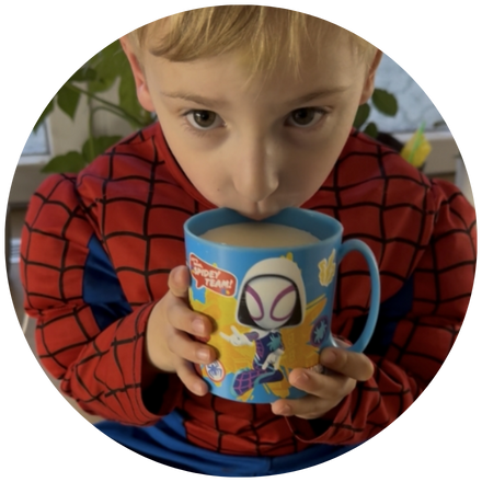 Chlapec v kostýmu Spider-Mana usrkává z hrnku s motivem Spider-Mana.