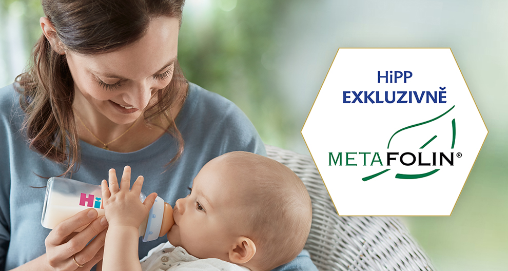 Žena krmí dítě lahví, zatímco na šestiúhelníkové reklamě jsou zobrazena slova "HiPP EXKLUZIVNE" a značka "METAFOLIN®".