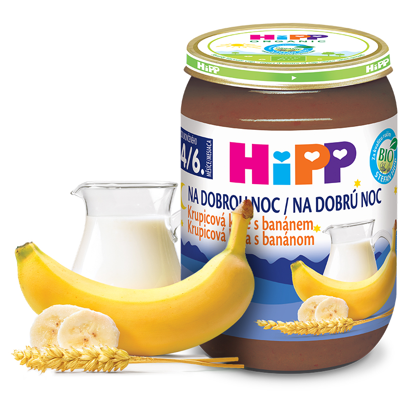Sklenička dětské výživy Hipp s banánovou příchutí, ke které je přiložen džbánek mléka a banán.