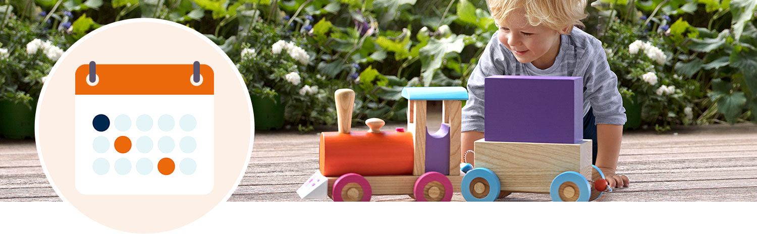 A child is playing with a toy train in a garden.