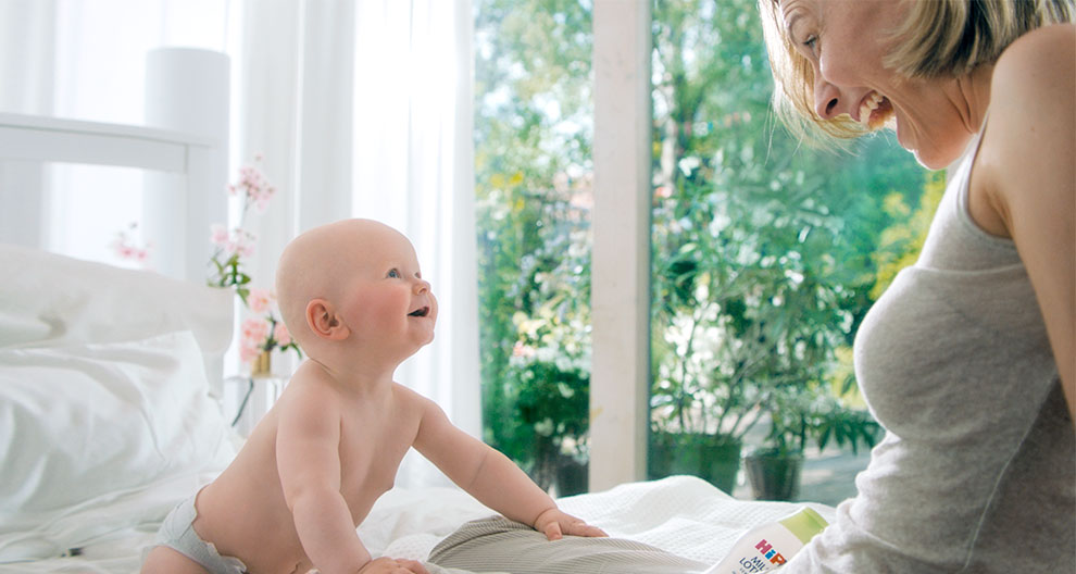 A woman and a baby are engaged in a playful interaction in a bright, sunlit room.