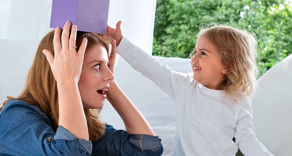 A woman and a child playfully interact with a purple box.